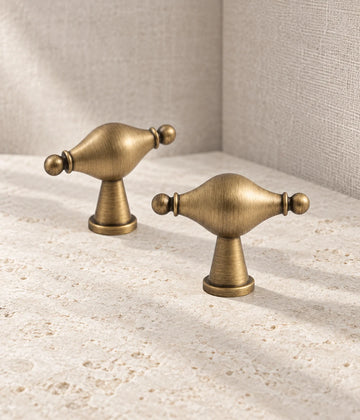 Antique brass urn-shaped spindle T-knobs arranged on pale limestone