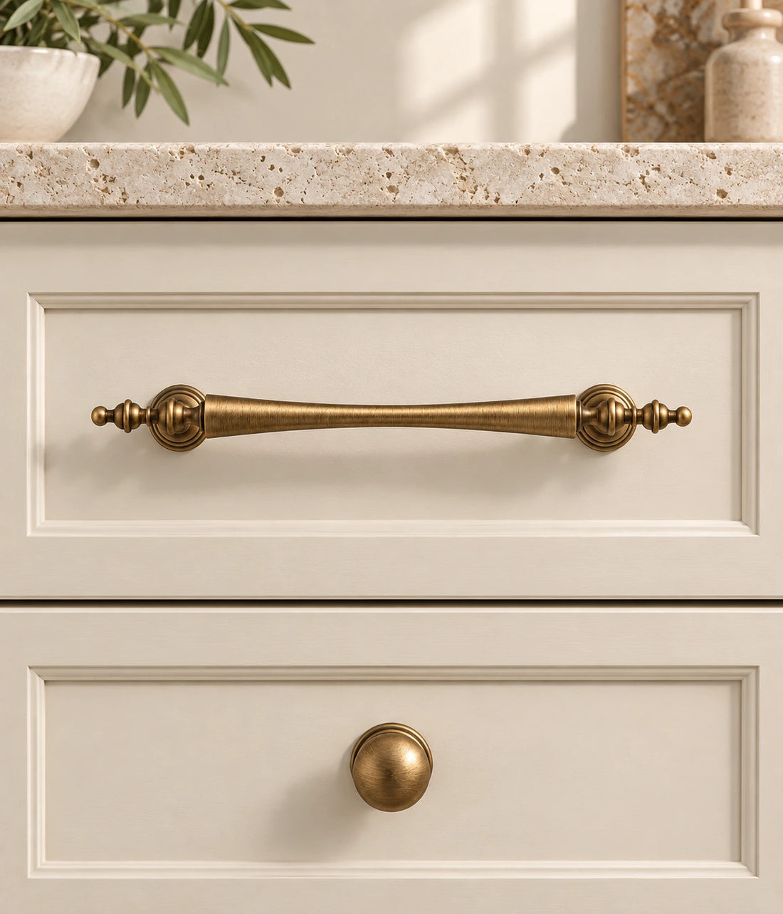 Antique brass waisted finial cabinet pulls and stepped-base ball knob on ivory limestone
