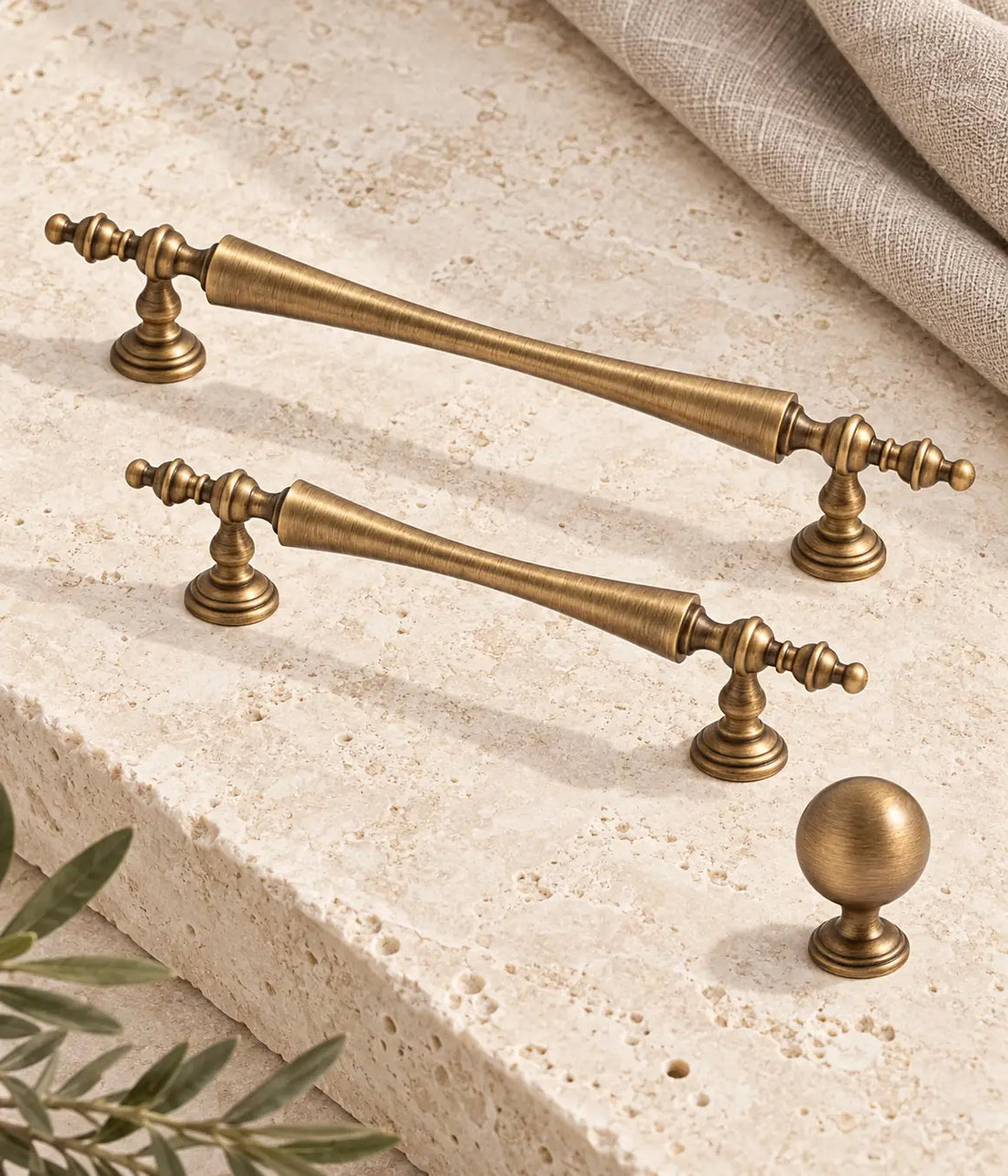 Antique brass waisted finial cabinet pulls and stepped-base ball knob on ivory limestone