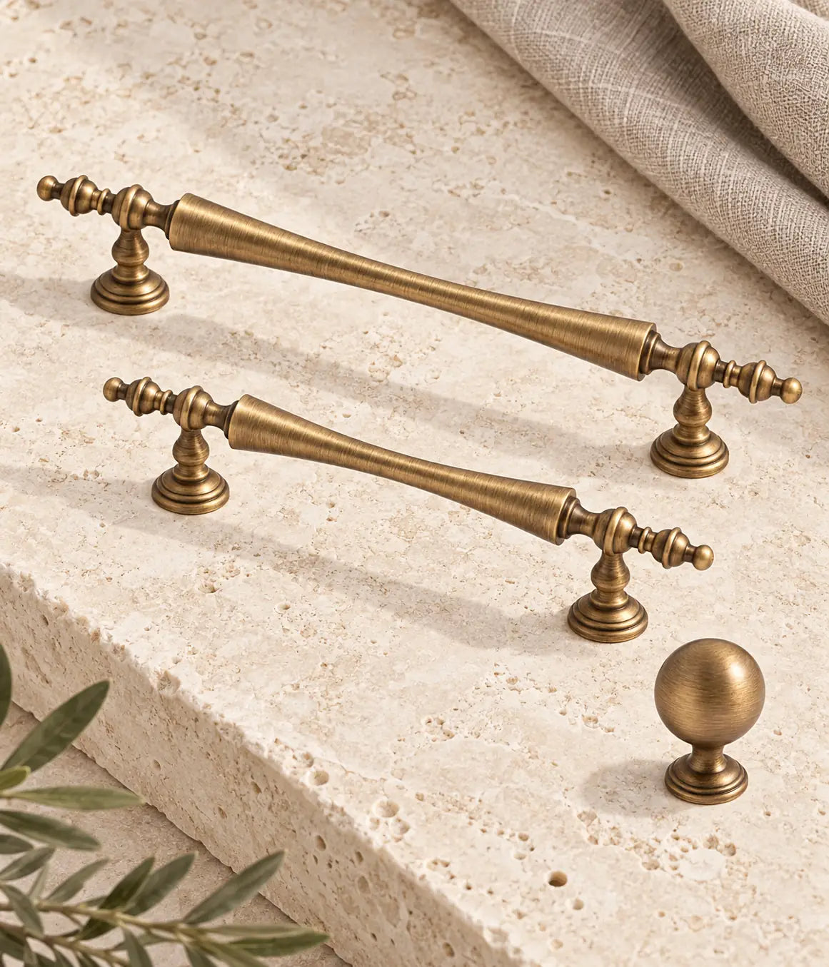 Antique brass waisted finial cabinet pulls and stepped-base ball knob on ivory limestone