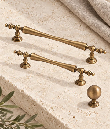 Antique brass waisted finial cabinet pulls and stepped-base ball knob on ivory limestone