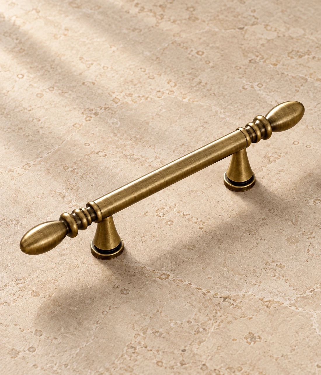 Antique Brass Water-Drop Cabinet Pulls on warm ivory limestone
