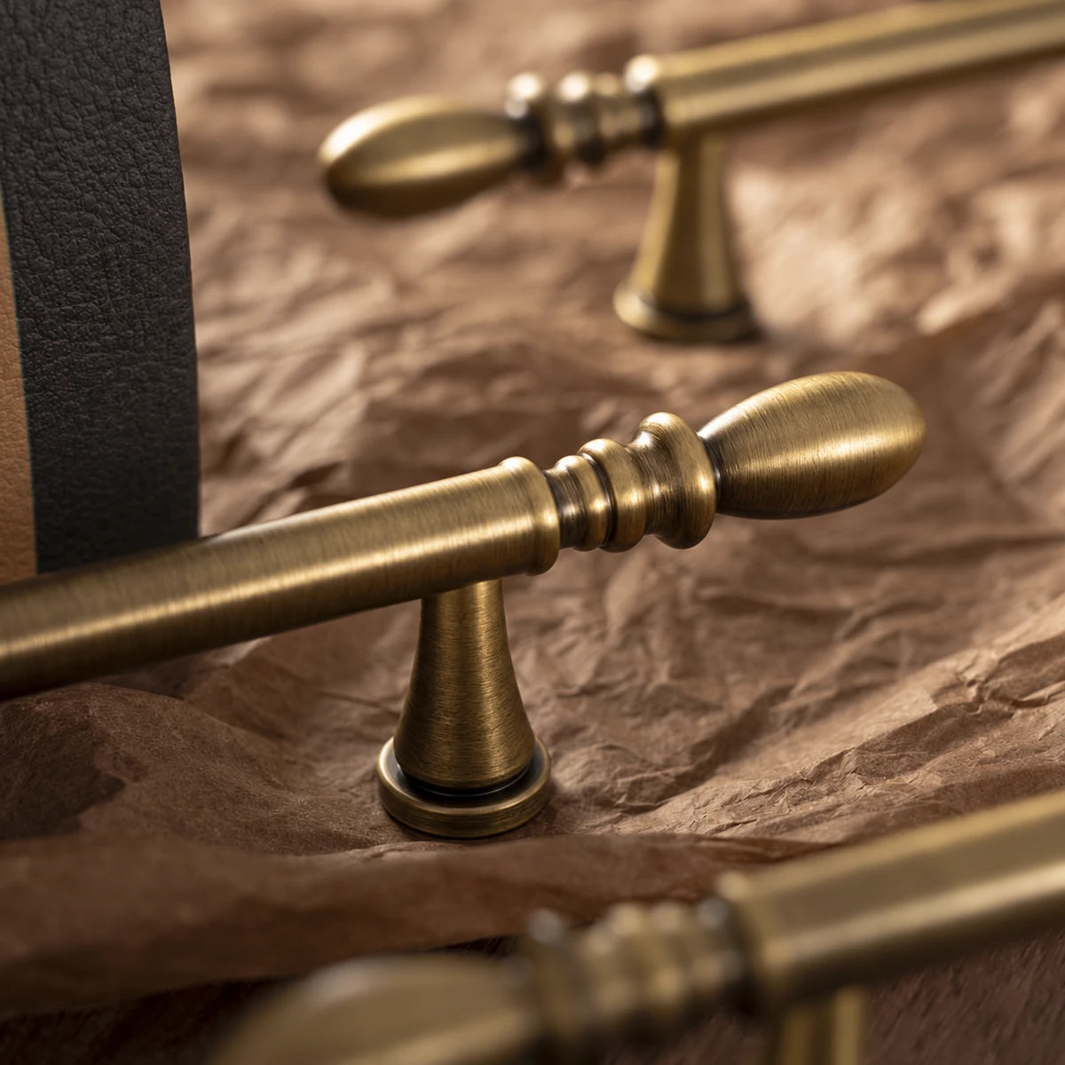 Antique brass water-drop cabinet pull close-up showing brushed finish and decorative detail