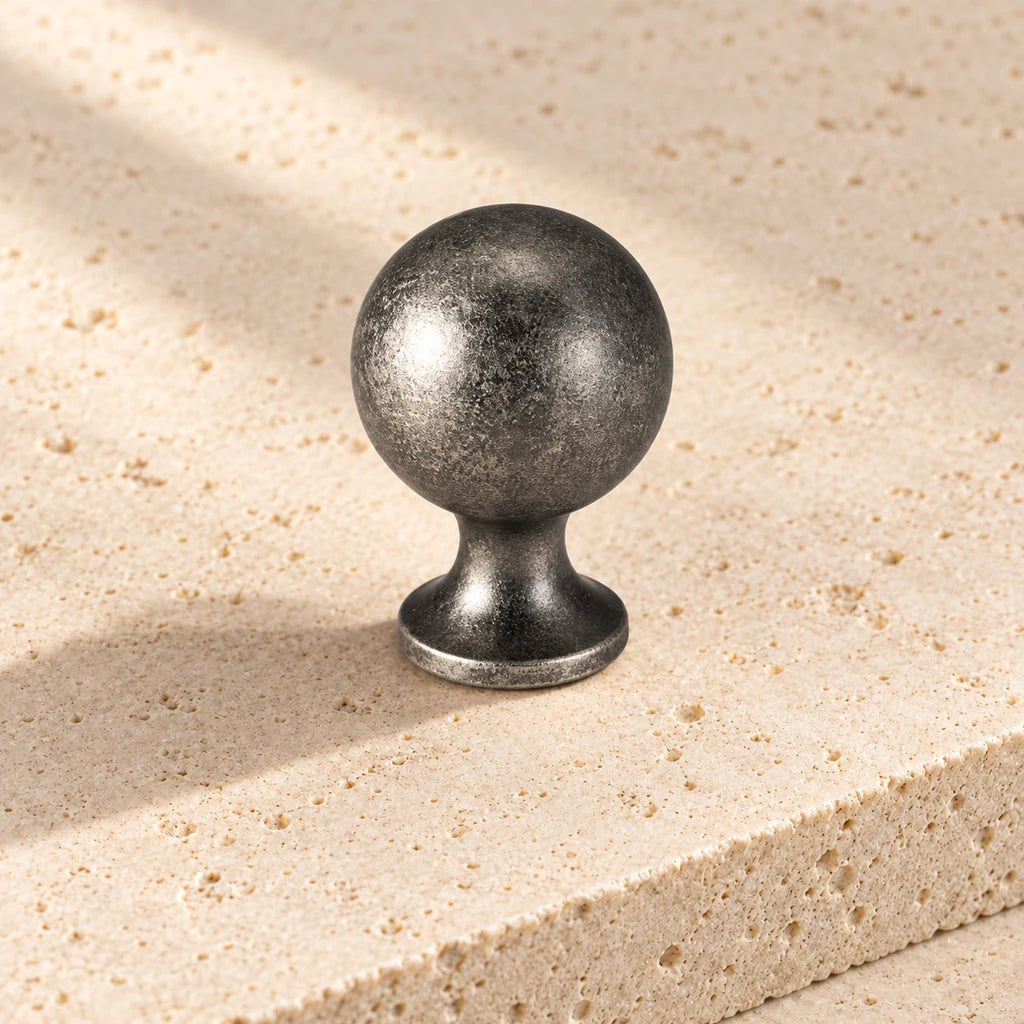 antique silver round cabinet knob on pale limestone.
