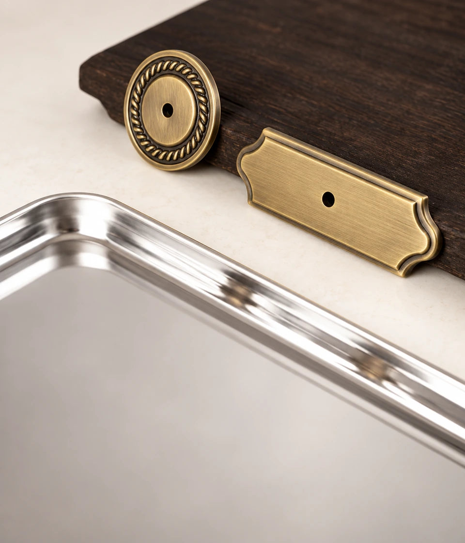 Antique brass knob backplates displayed against dark wood