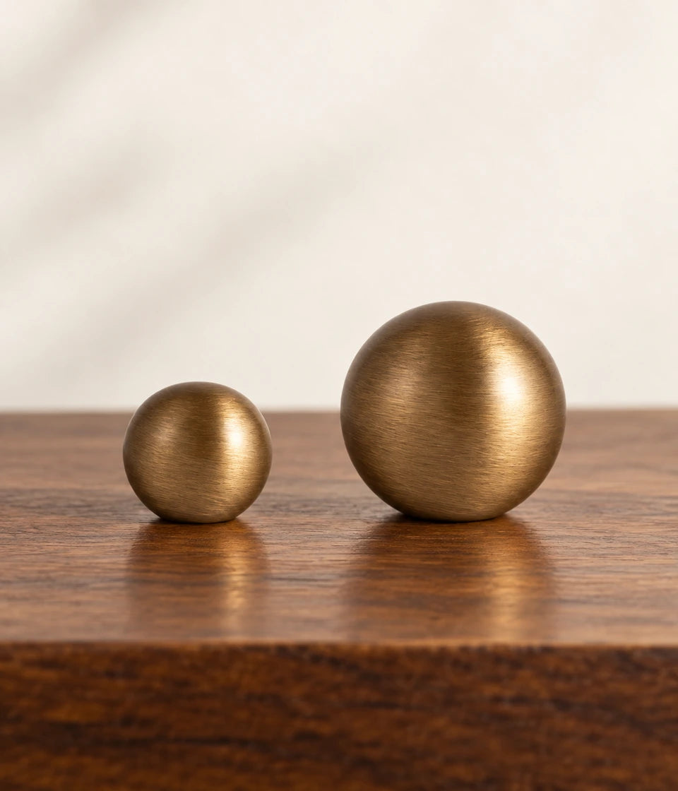 Small and large stemless antique brass ball knobs on dark wood