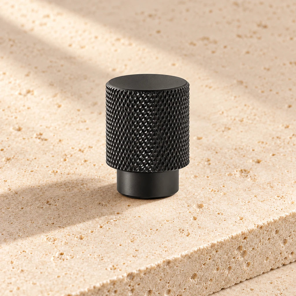 black cross knurled cabinet knob on pale limestone.