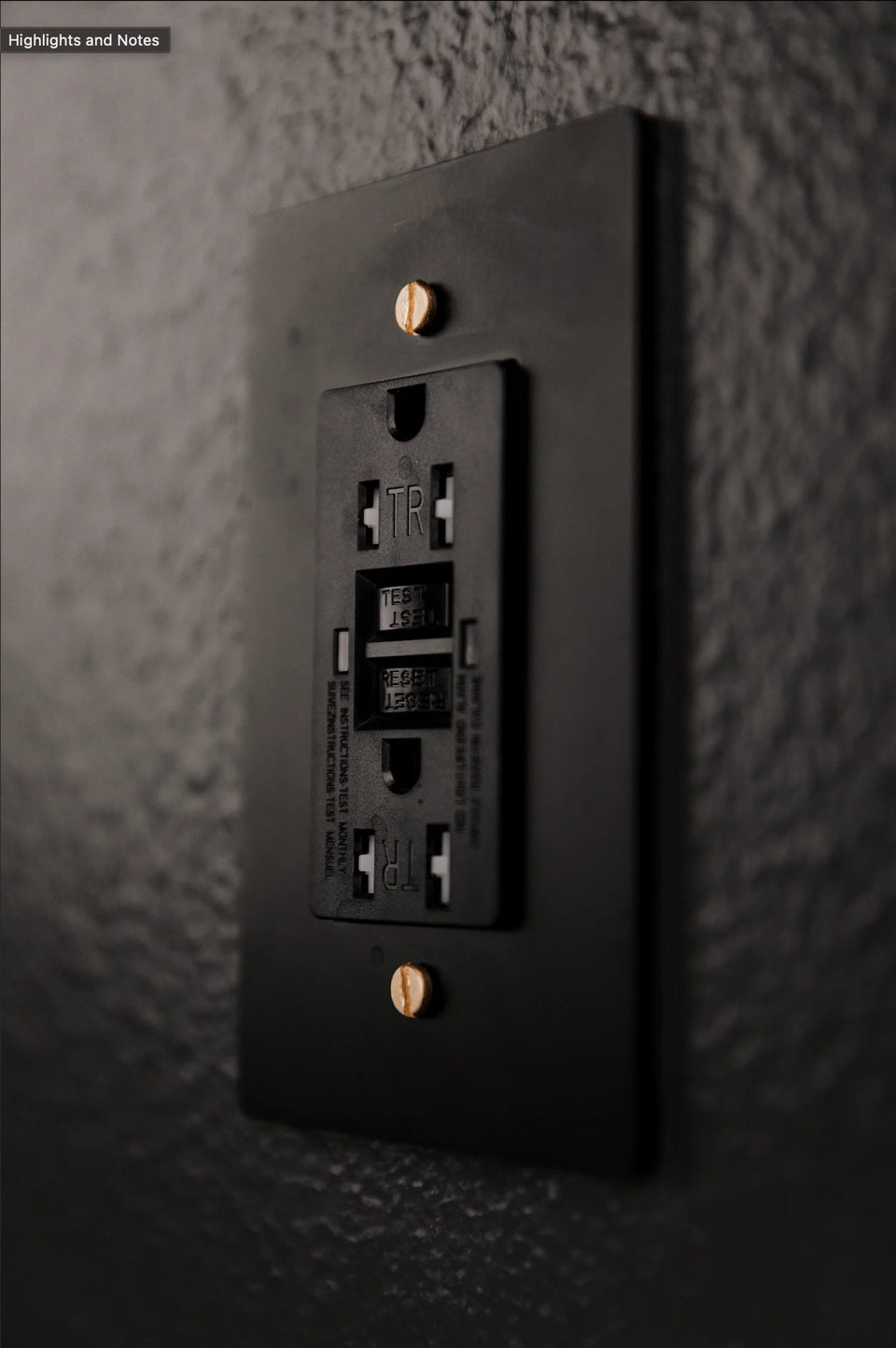 Black GFCI outlet set into a wall.