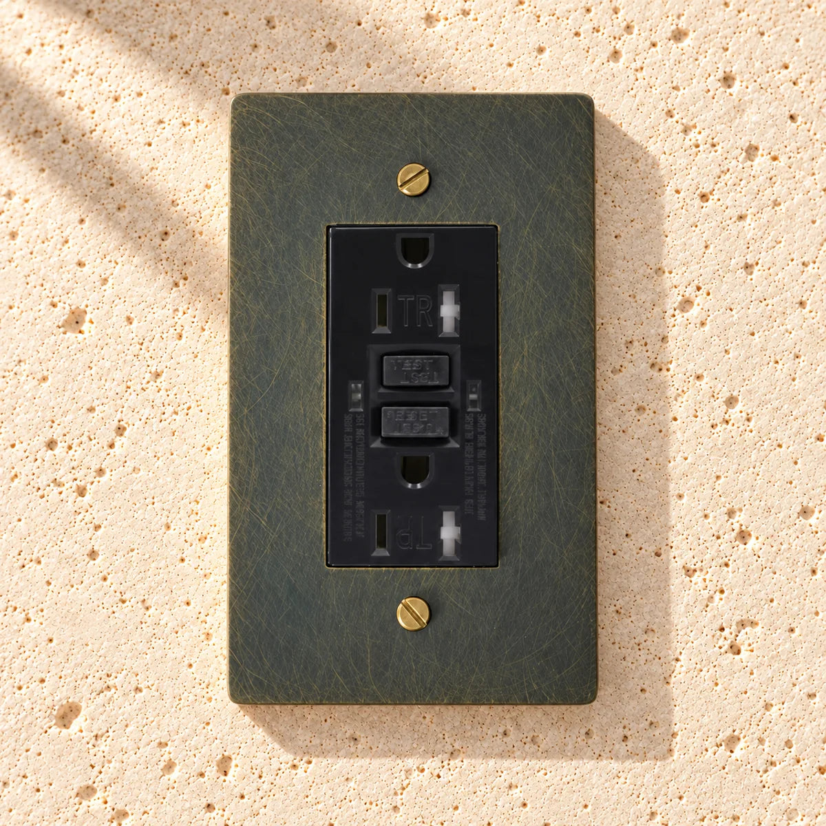 Brass GFCI Electrical Outlet — 15A/20A on sunlit pale limestone