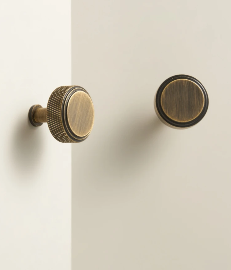 Pair of bronze diamond  cabinet knobs on a beige background.