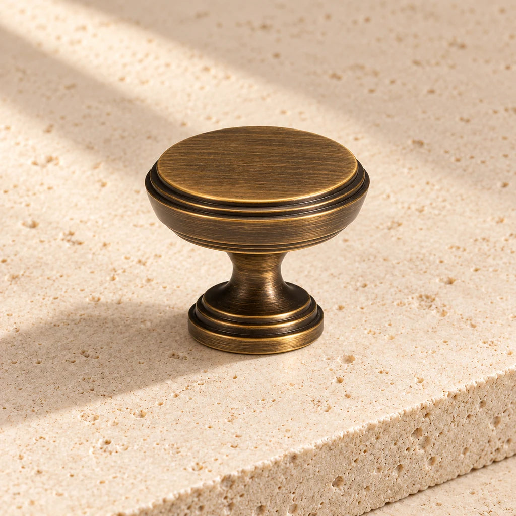 brushed bronze round cabinet knob on pale limestone.
