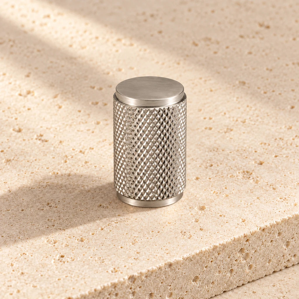 brushed nickel knurled cylinder knob on pale limestone.