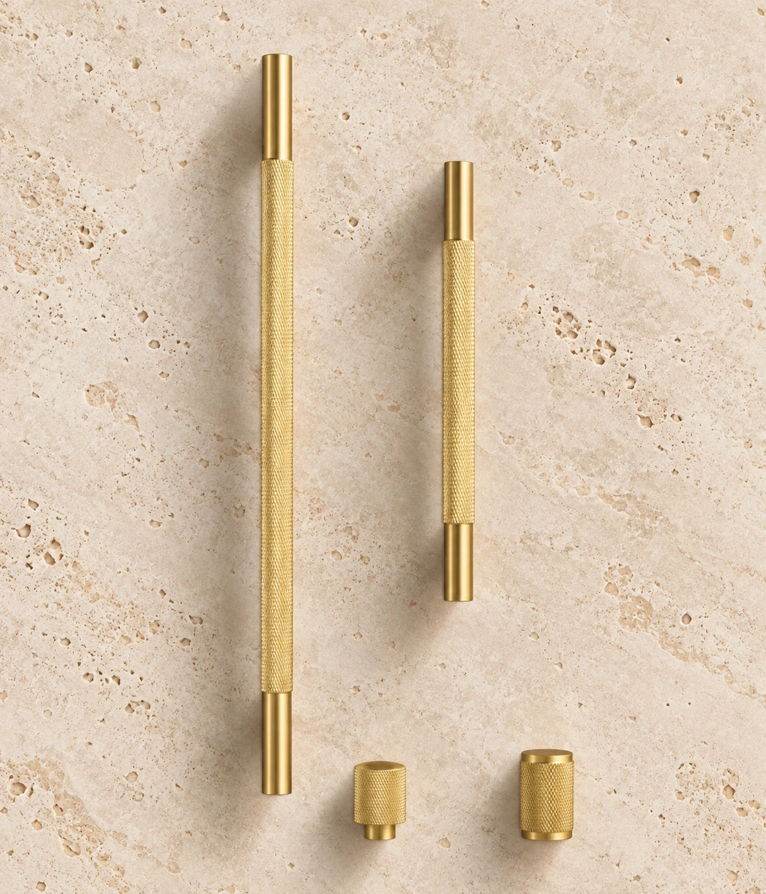 Cross-Knurled Brass Cabinet Pulls & Knobs arranged on warm limestone