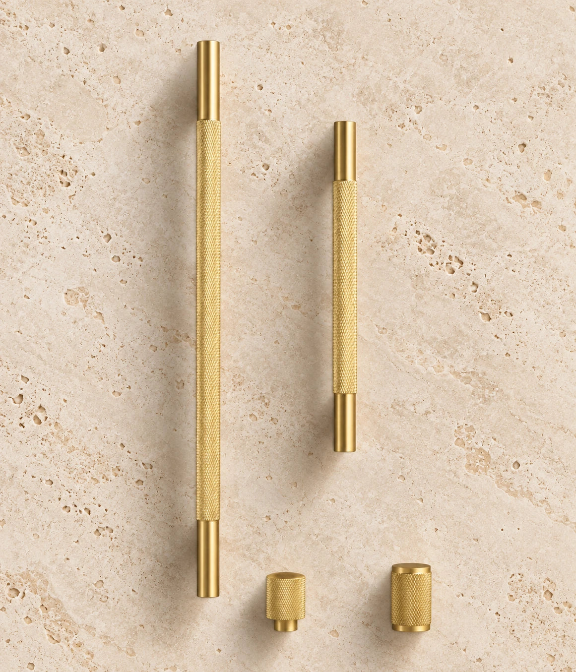 Cross-Knurled Brass Cabinet Pulls & Knobs arranged on warm limestone