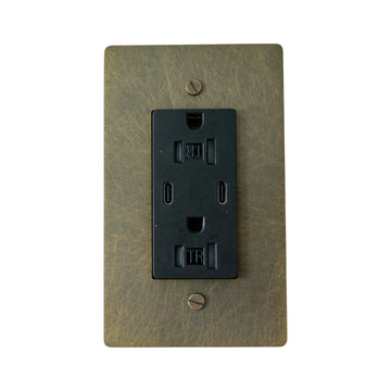 Black electrical outlet on a bronze wall plate against a white background