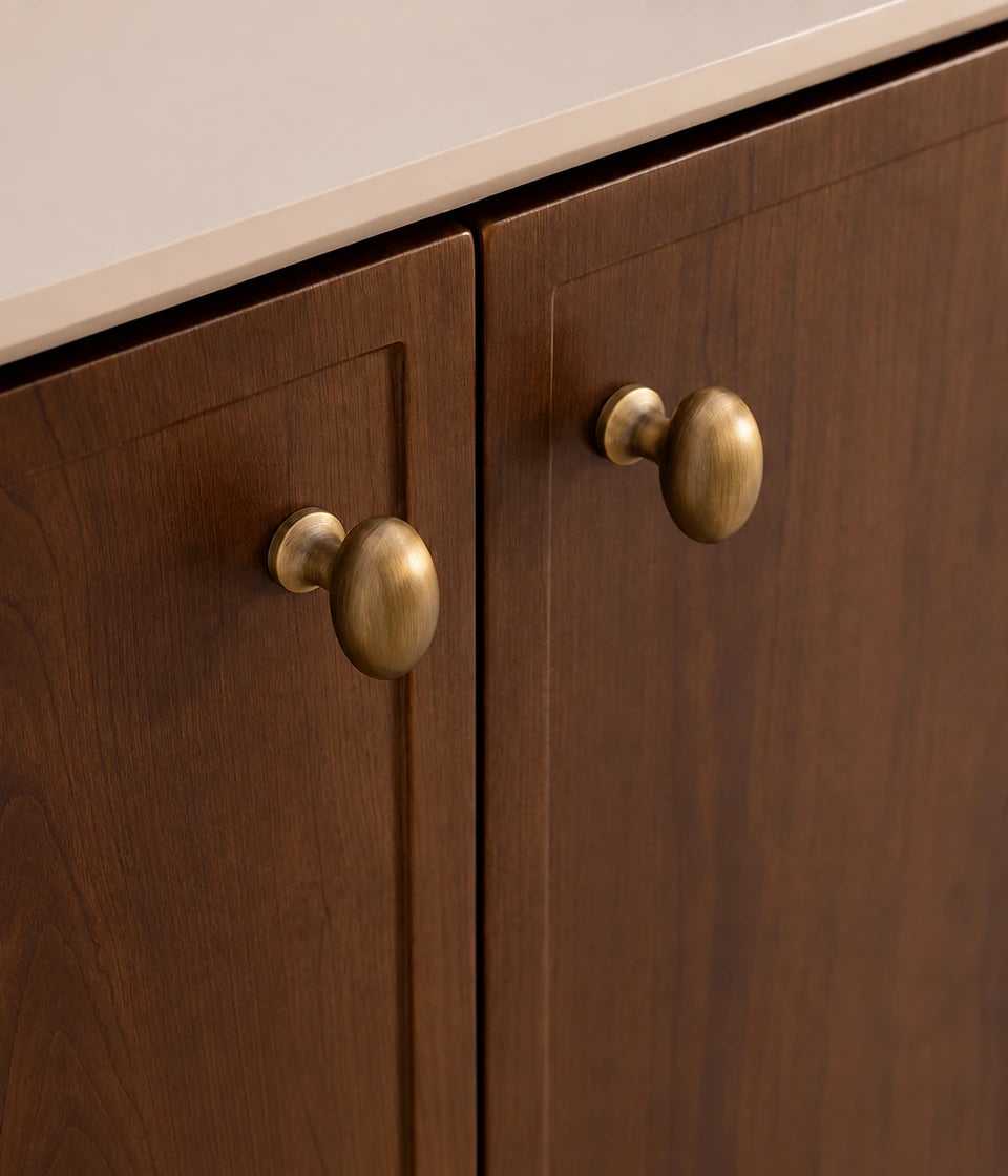 Antique brass pedestal egg knobs installed on dark wooden cabinet doors