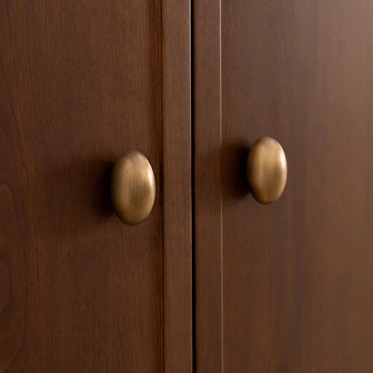 Stemless antique brass oval knobs mounted on wooden cabinet doors