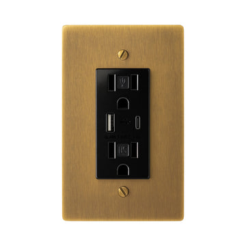 Antique brushed brass wall plate with black electrical outlet on a white background