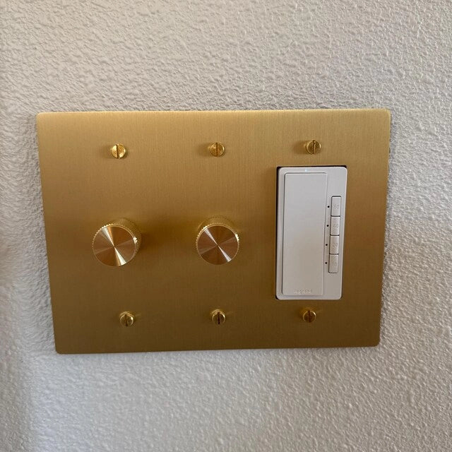 Brass dimmer and matching outlet installed above a pale kitchen countertop.