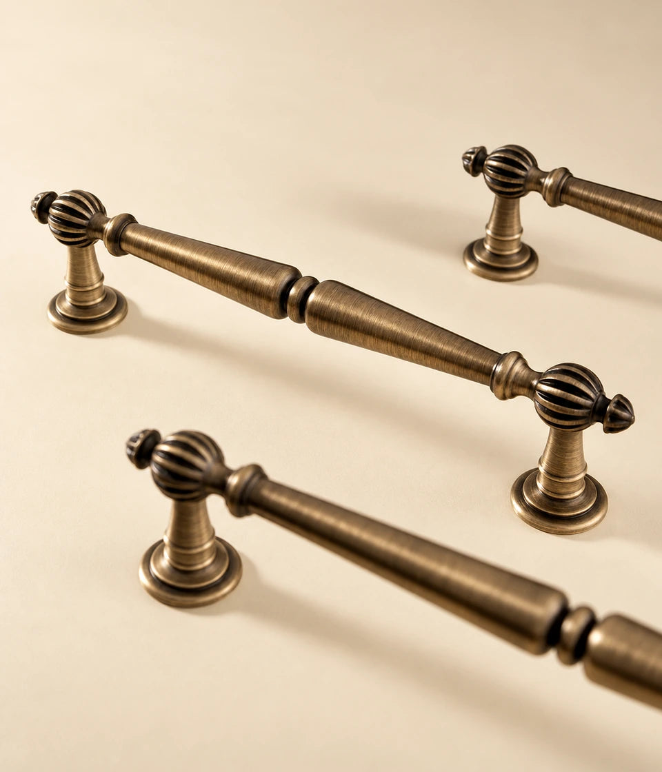 Fluted ball cabinet pulls in antique brushed brass arranged on a cream tabletop