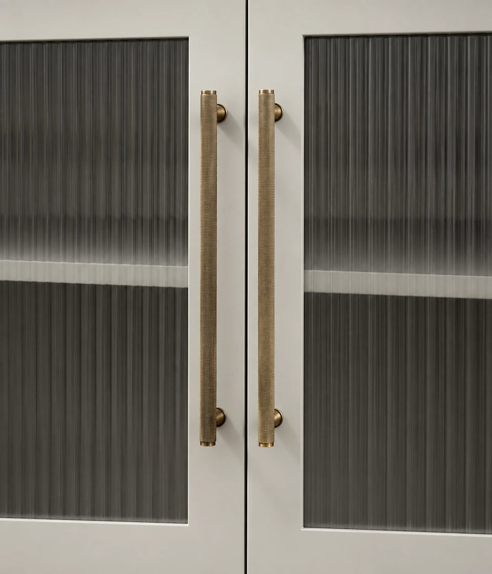 Full knurled antique brass cabinet bar pulls installed on fluted glass cabinet doors