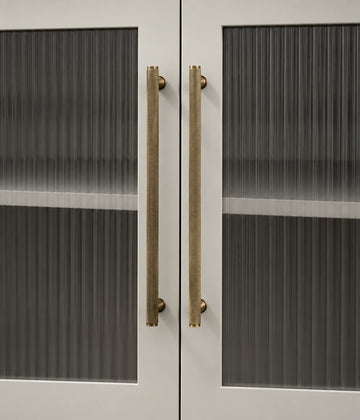 Full knurled antique brass cabinet bar pulls installed on fluted glass cabinet doors