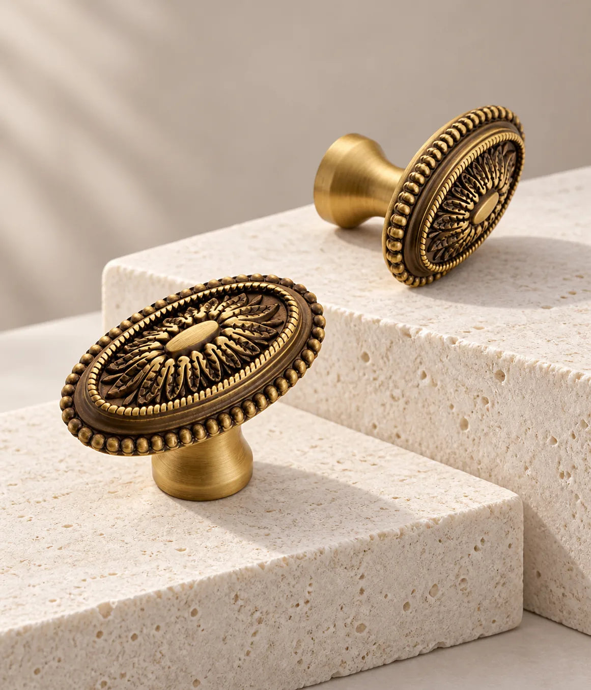 Acanthus medallion cabinet knobs in antique brass arranged on stepped ivory limestone