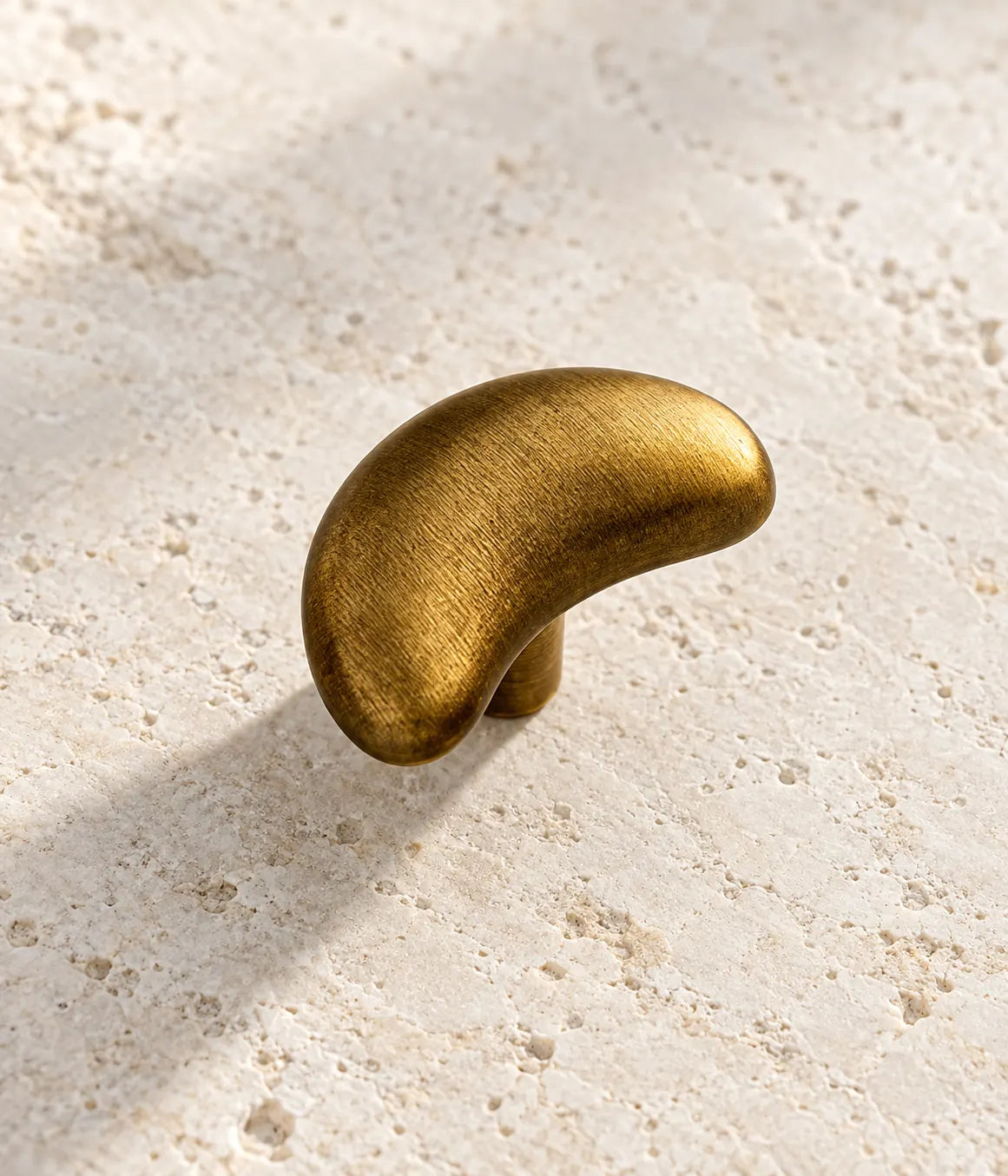 Smooth curved face and rounded ends of antique brass crescent knob