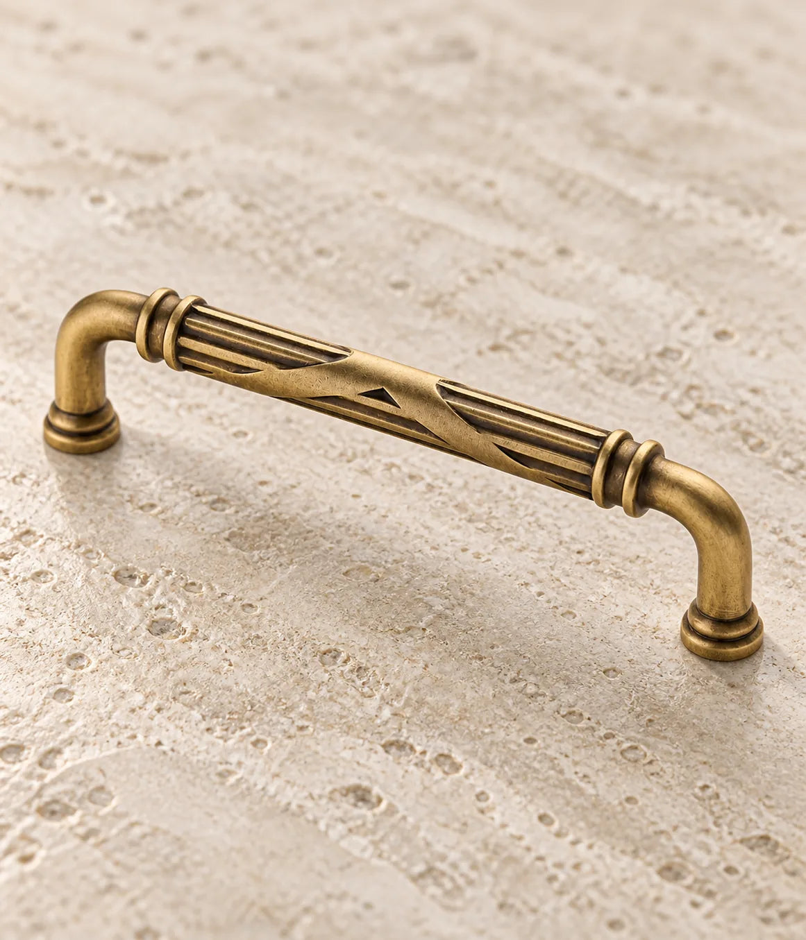 Close-up of fluted grip, crossed ribbon and double collars on antique brass cabinet pull