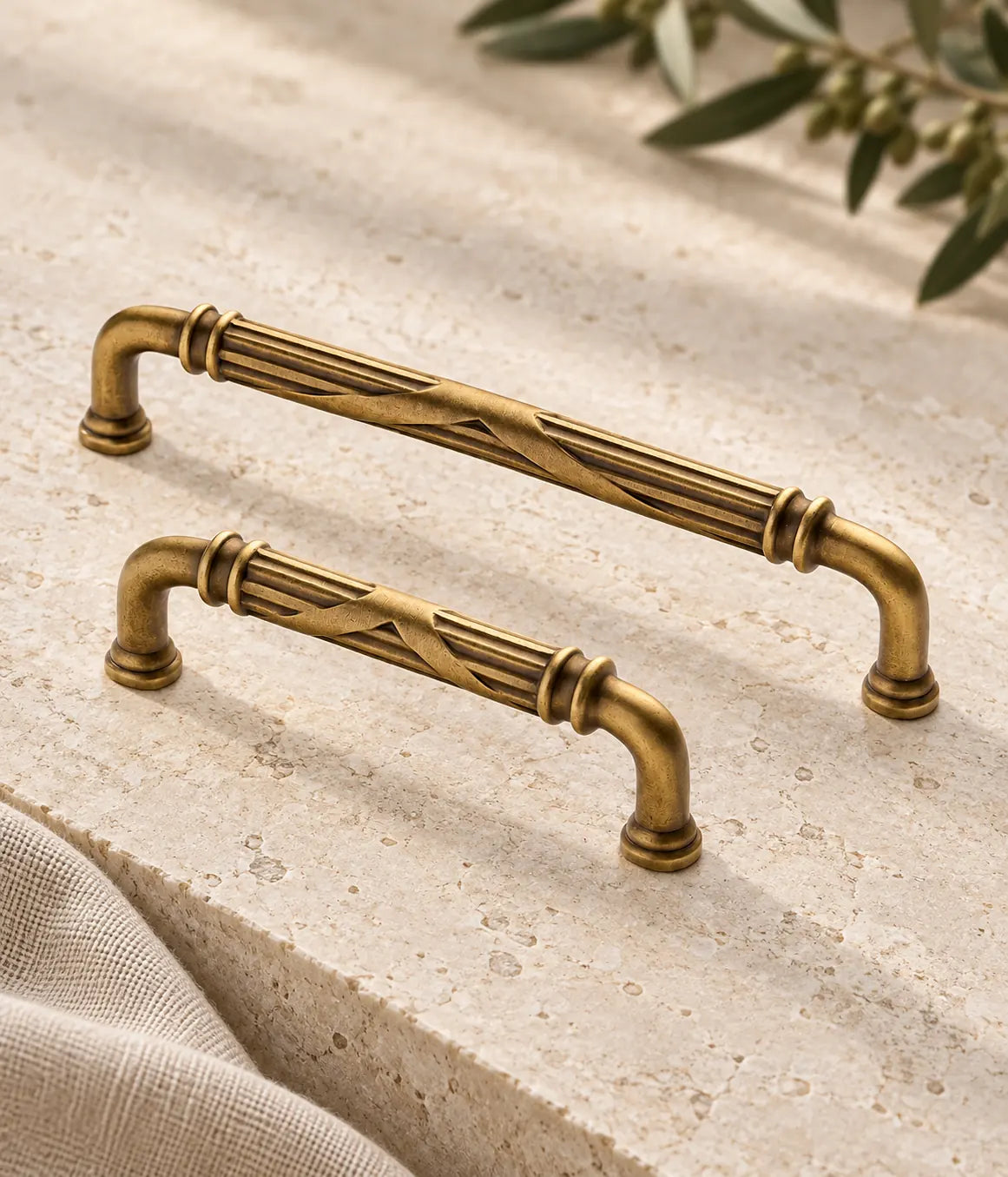 Long and short antique brass cross-ribbon handles arranged on pale limestone