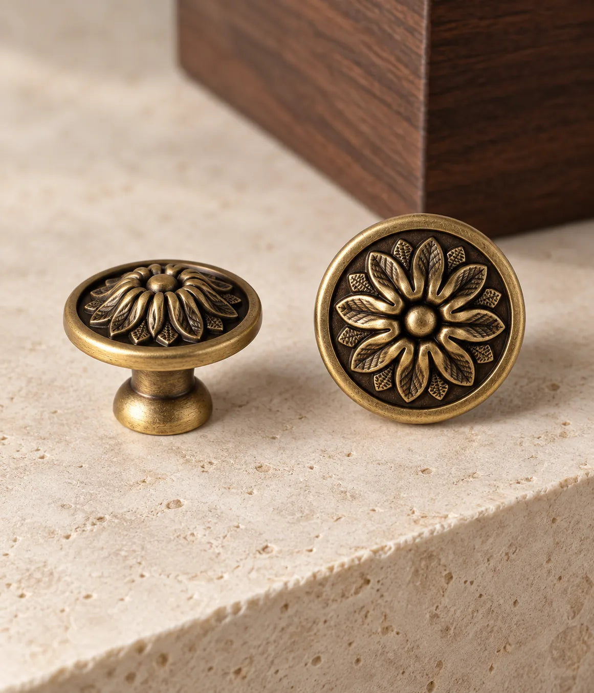 Antique brass floral disc knobs styled beside dark walnut on pale limestone