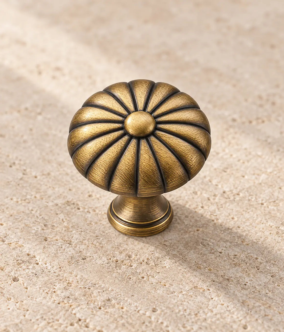 Antique brass fluted button cabinet knobs arranged on pale limestone