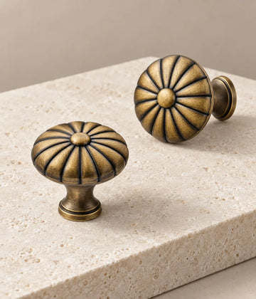 Antique brass fluted button cabinet knobs arranged on pale limestone
