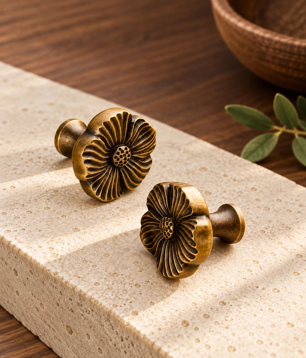 Antique brass flower knobs styled on pale limestone beside walnut