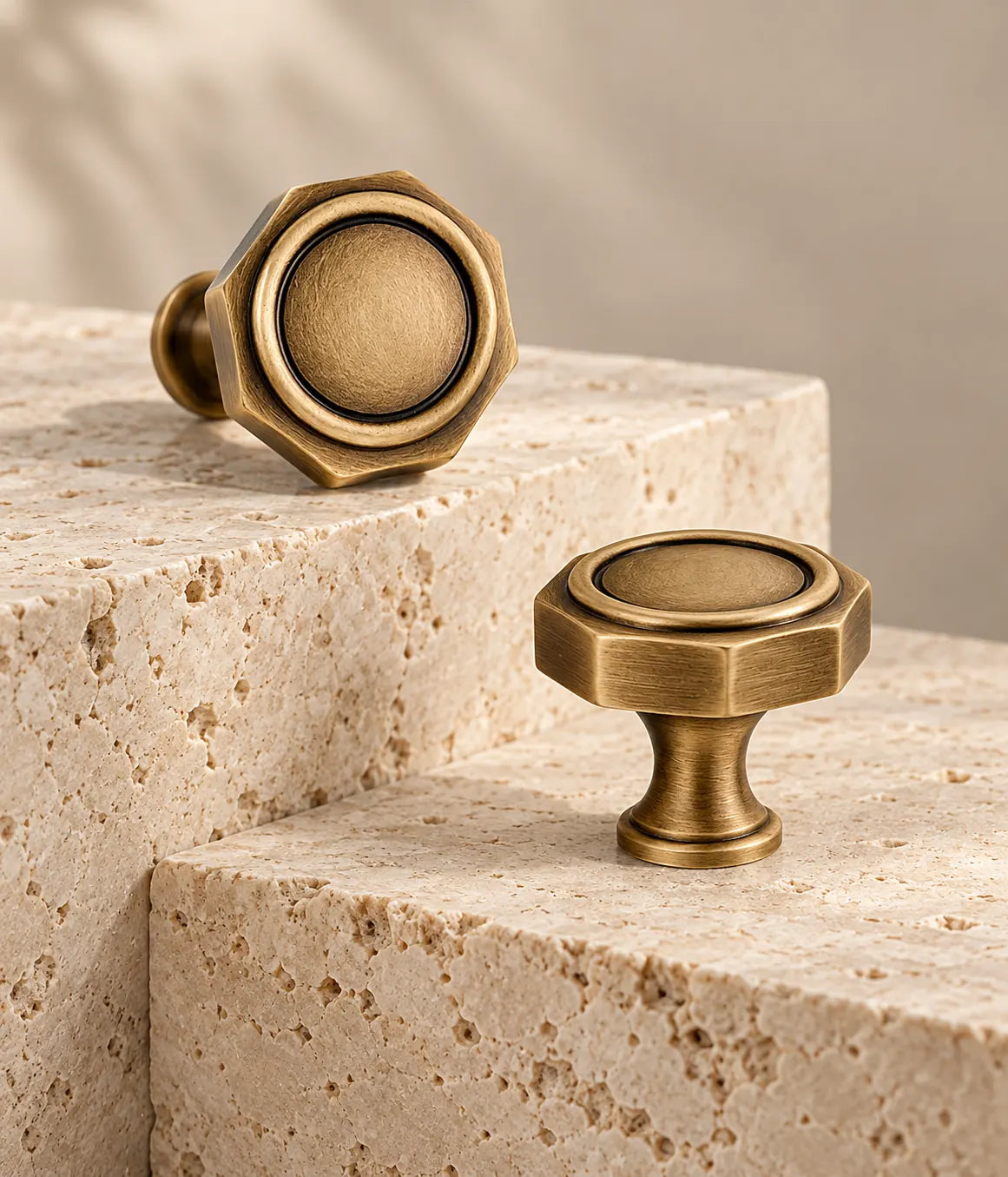 Antique brass octagonal cabinet knobs with circular insets on travertine steps