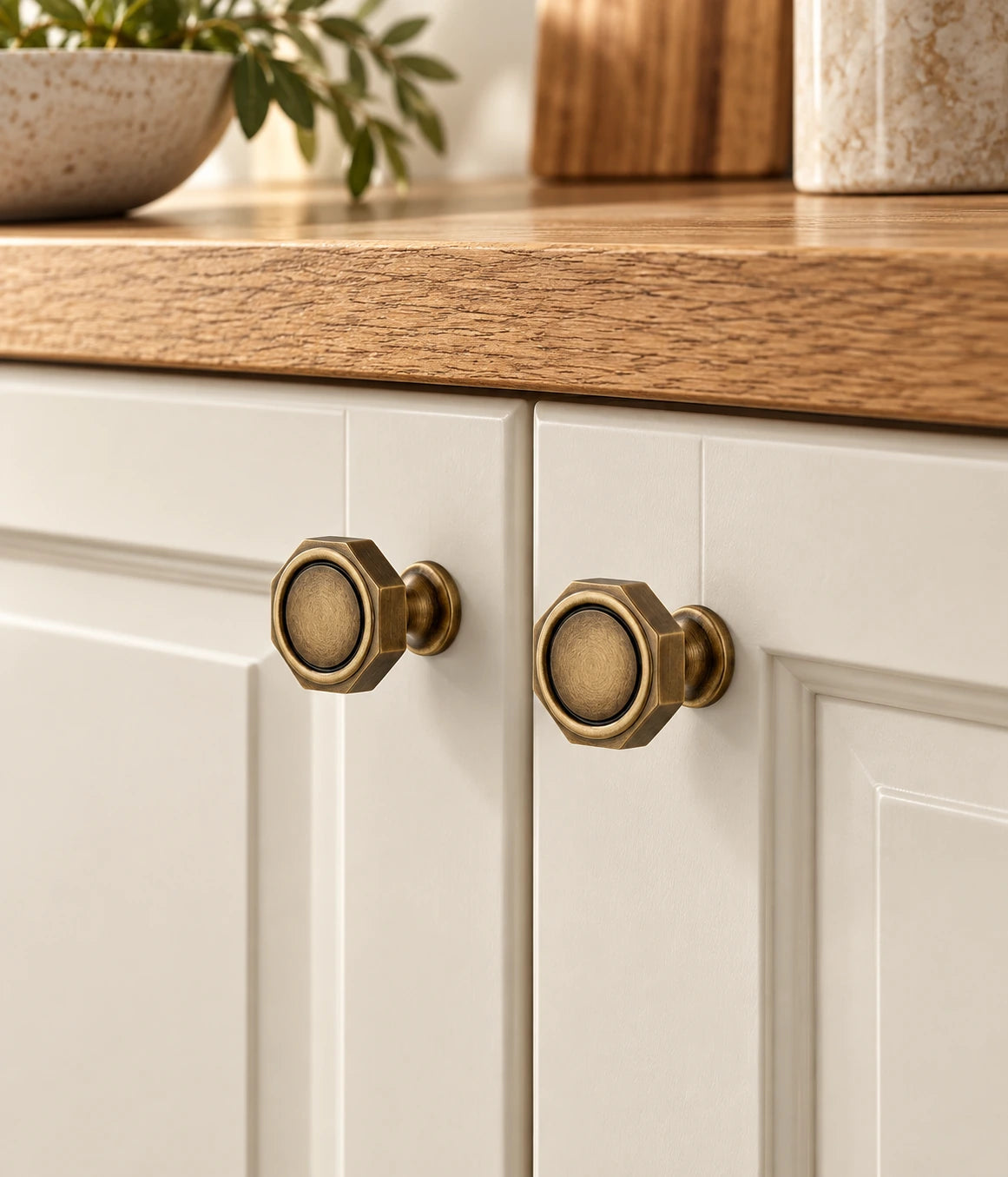 Antique brass octagonal knobs installed on ivory cabinet doors beneath oak
