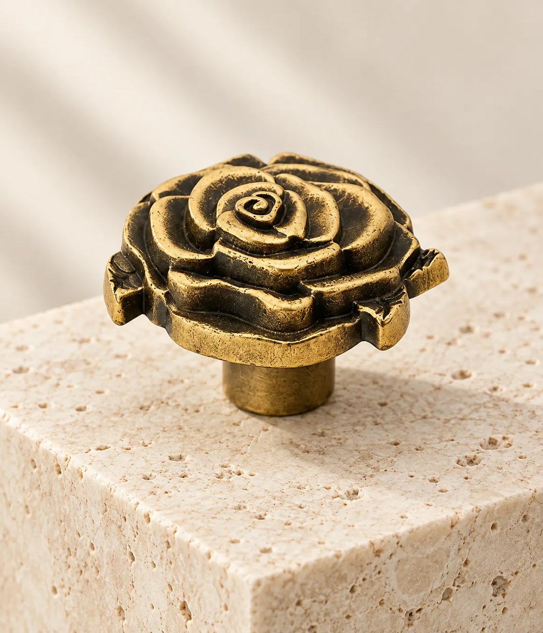 Antique brass rose cabinet knobs arranged on ivory limestone