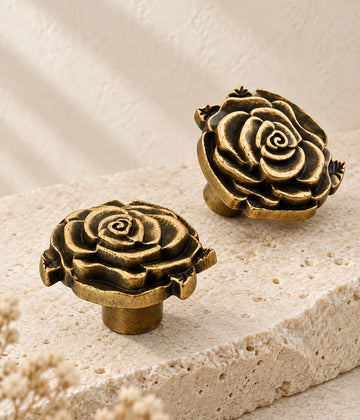 Antique brass rose cabinet knobs arranged on ivory limestone