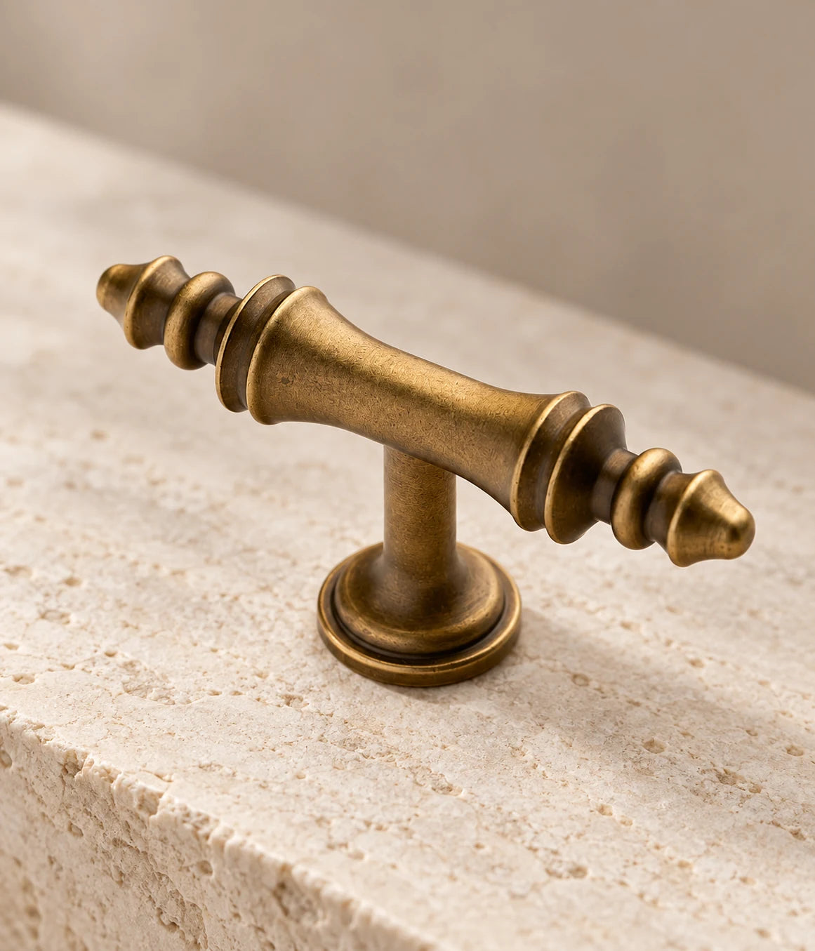Close-up of pointed stepped finials and waisted grip on antique brass T-knob