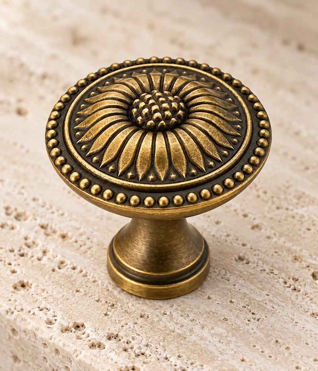 Antique brass sunflower cabinet knobs arranged on ivory limestone