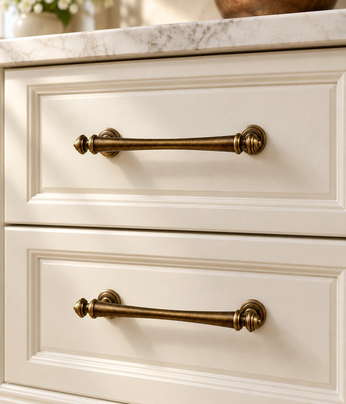 Antique brass turned-finial pulls mounted on warm ivory cabinet drawers