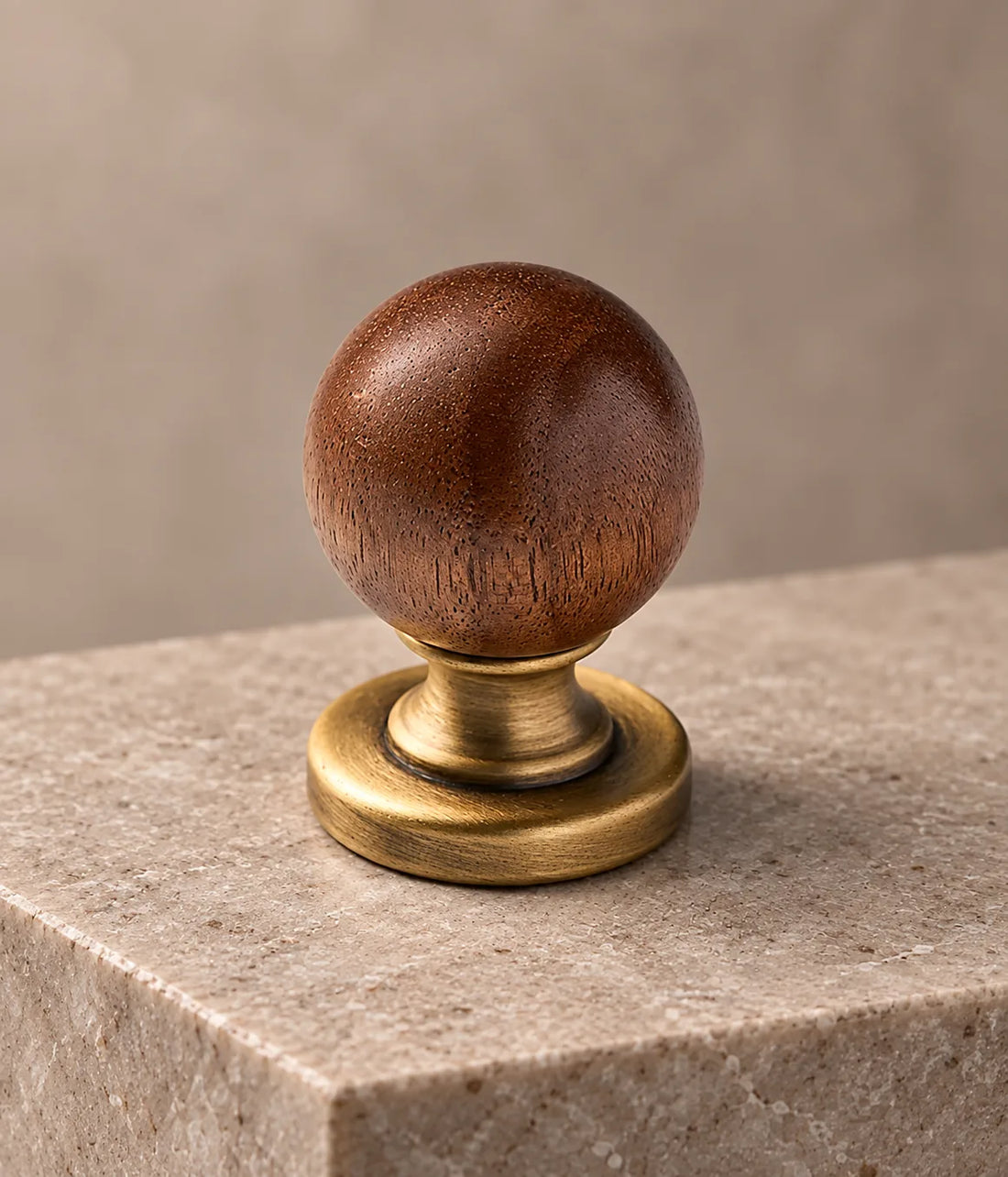 Walnut ball-end antique brass pulls and matching round cabinet knob arranged on pale limestone