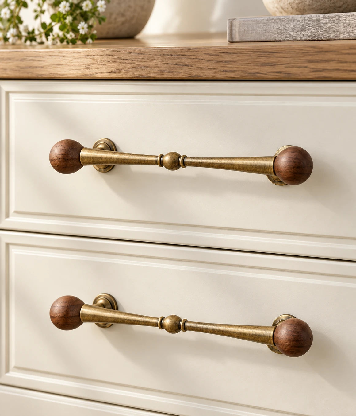 Walnut and antique brass ball-end pulls on cream drawer fronts