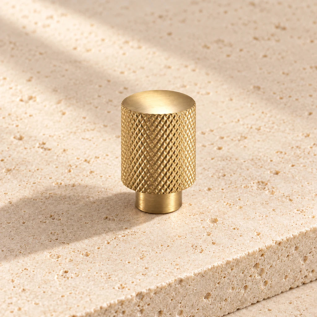 gold brass knurled cylinder knob on pale limestone.