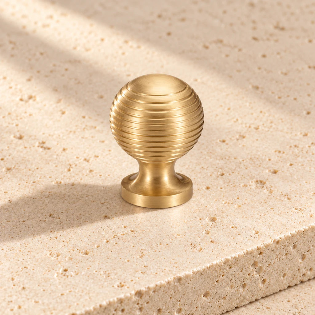 gold brass ribbed ball knob on pale limestone.