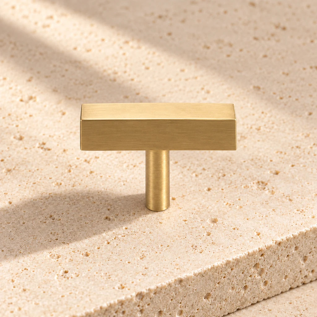 gold brass square t knob on pale limestone.