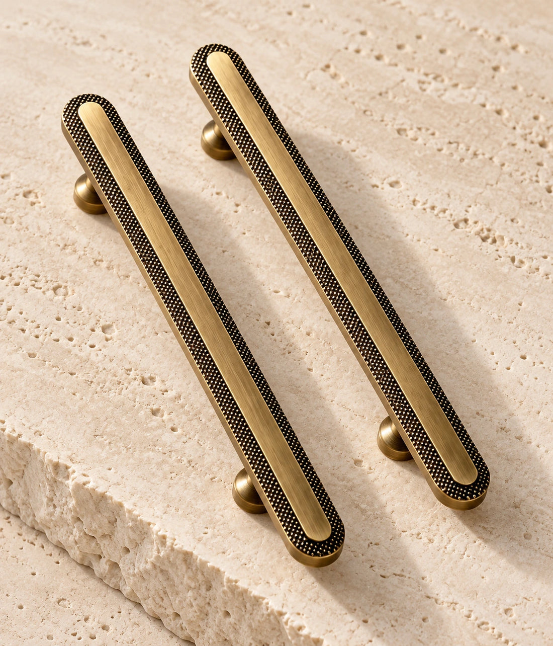 Antique Brass Knurled Rim Cabinet Pulls & Knob on warm limestone, showing the antique brushed brass finish