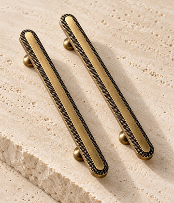 Antique Brass Knurled Rim Cabinet Pulls & Knob on warm limestone, showing the antique brushed brass finish