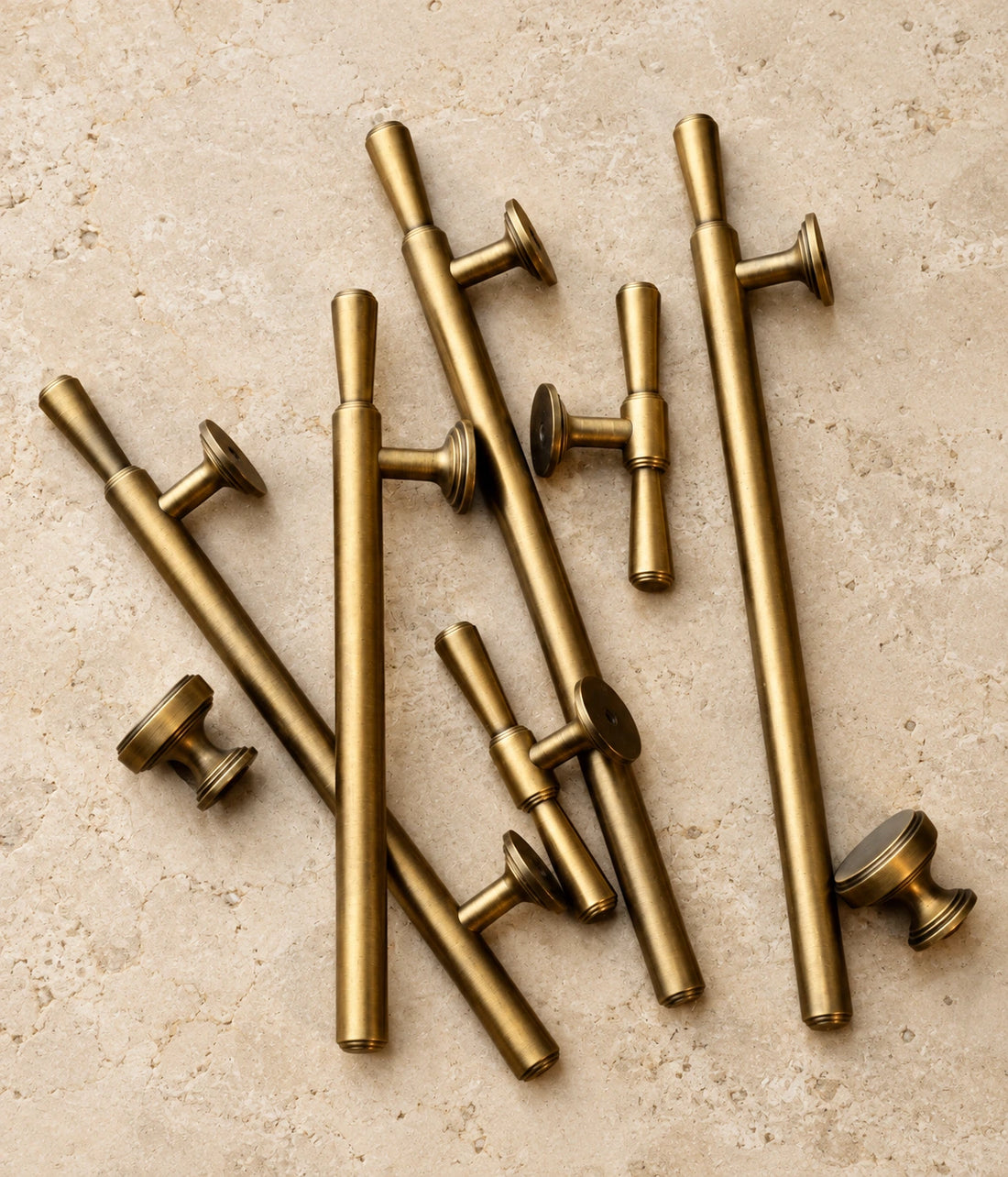 Antique brass classic bar cabinet pulls, T-knobs and round knobs arranged on limestone