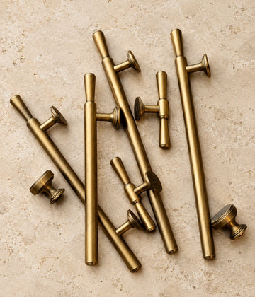 Antique brass classic bar cabinet pulls, T-knobs and round knobs arranged on limestone